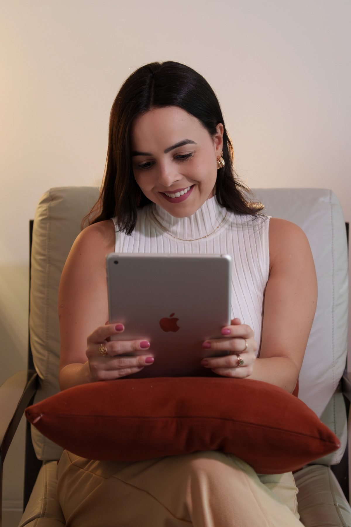 Jéssica Ladeia durante um atendimento online, sentada em uma poltrona com um tablet